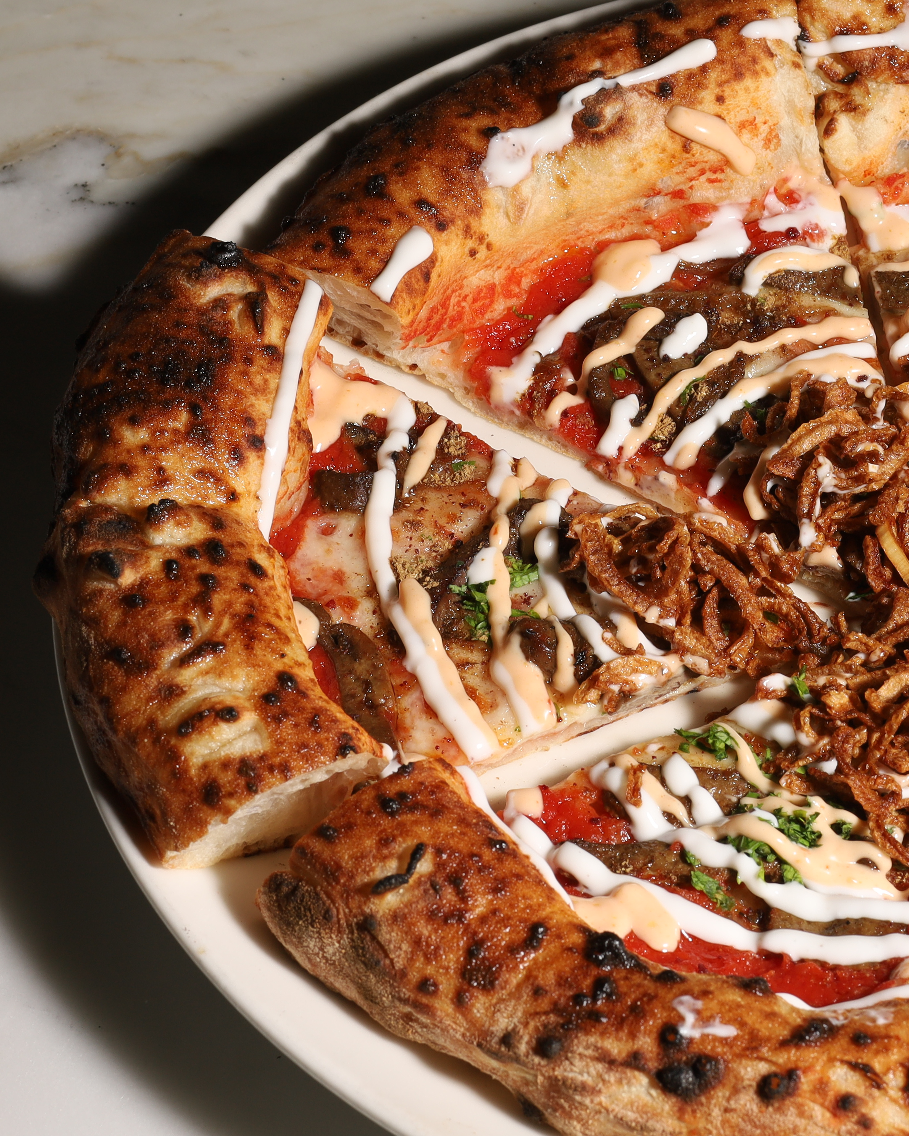 Close-up of a freshly baked MEMOS pizza with a charred, blistered crust
